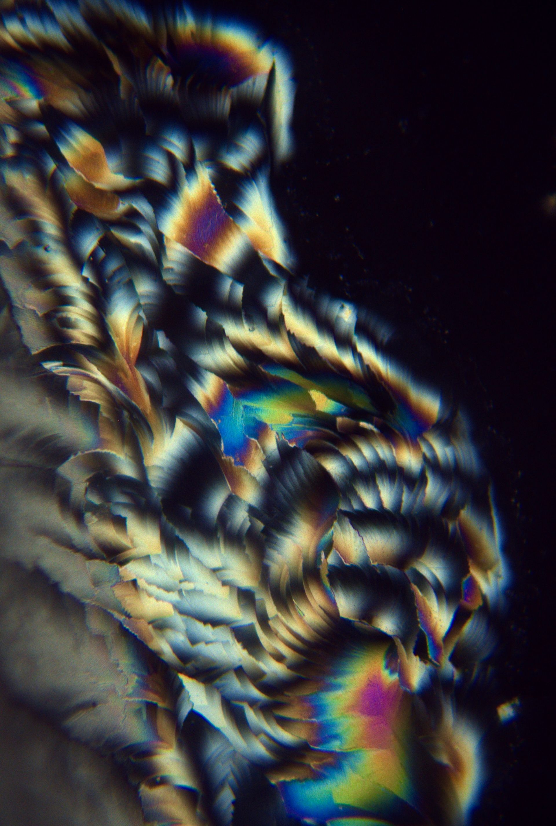 Pet memorial artwork showing blue and rainbow crystal patterns from ashes photographed under polarized light