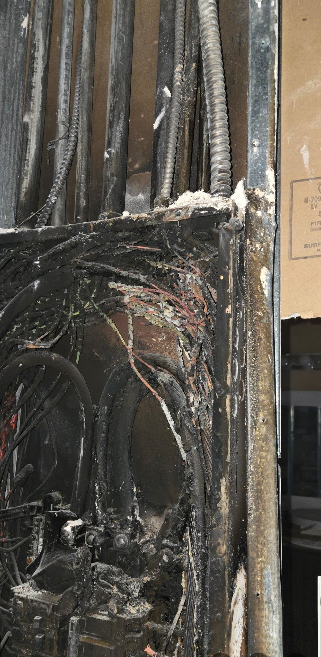 Close-up of a black wrought iron gate, showing fire damage and charring.