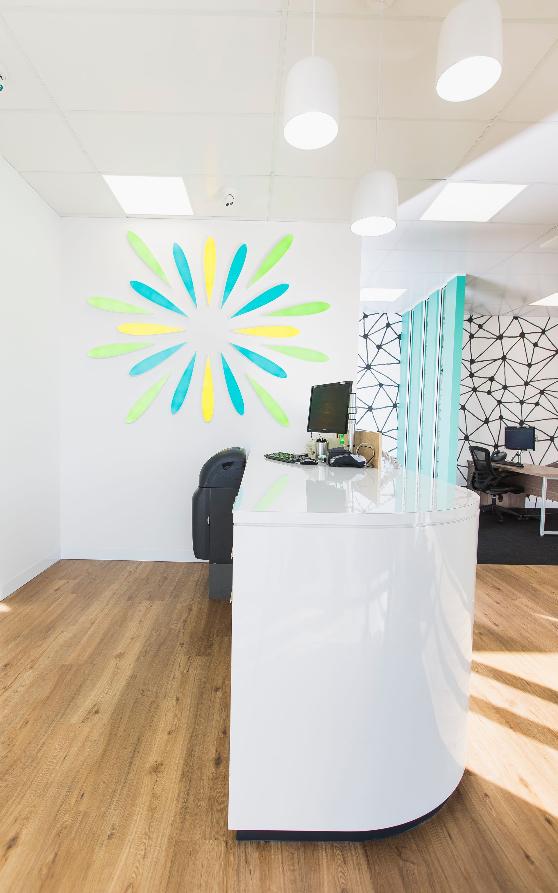 White Reception Desk With Colorful Wall Art and Hardwood Flooring — ATH Projects in Kirrawee, NSW