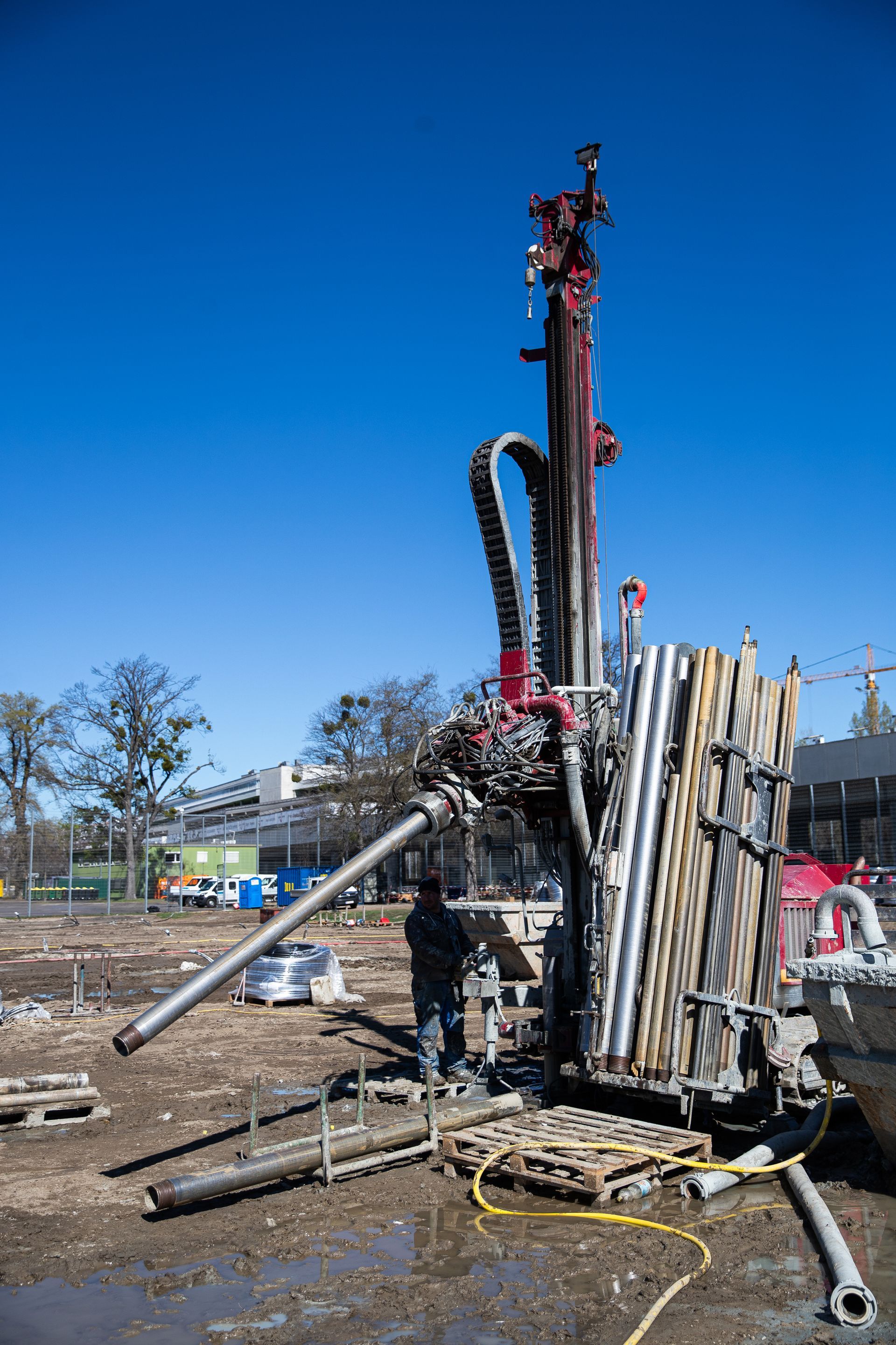 Auf einer schlammigen Baustelle arbeitet eine Bohranlage unter strahlend blauem Himmel.