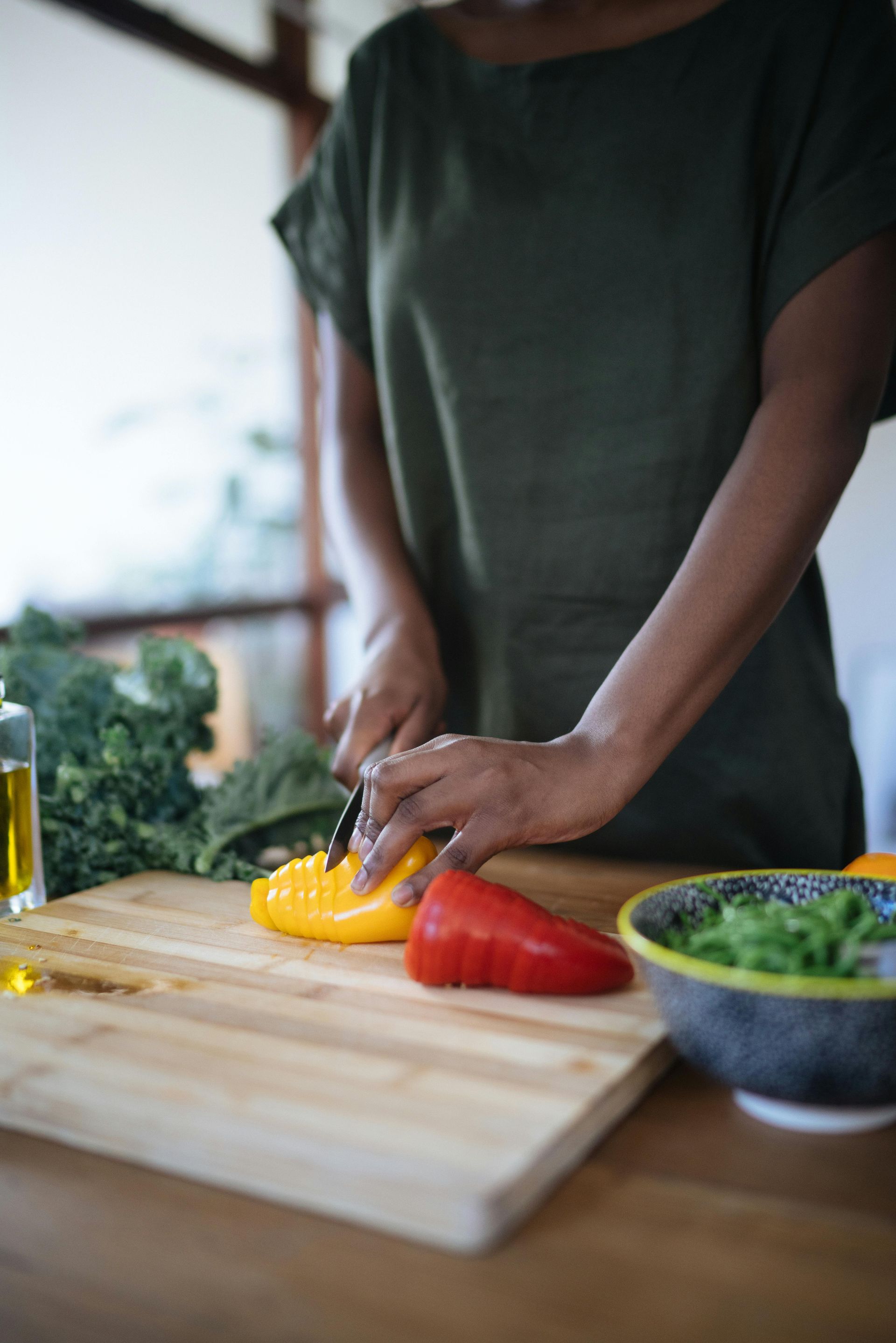 Une femme coupe des légumes sur une planche à découper.