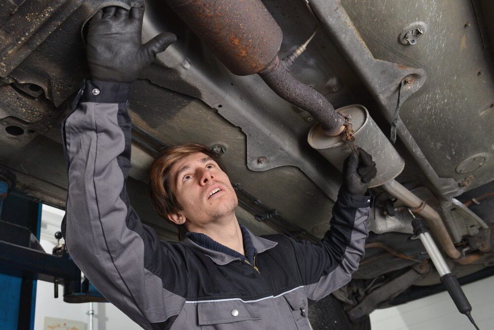 A Man Is Working On The Underside Of A Car — Carite Auto Repairs In Warana, QLD