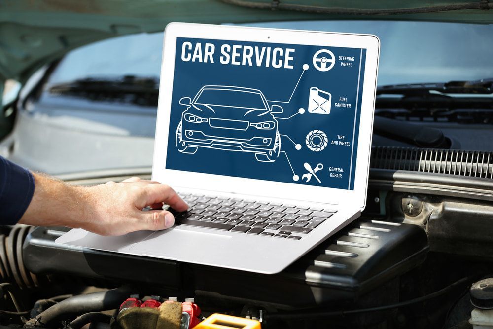 A Person Is Using A Laptop Computer Under The Hood Of A Car — Carite Auto Repairs In Warana, QLD