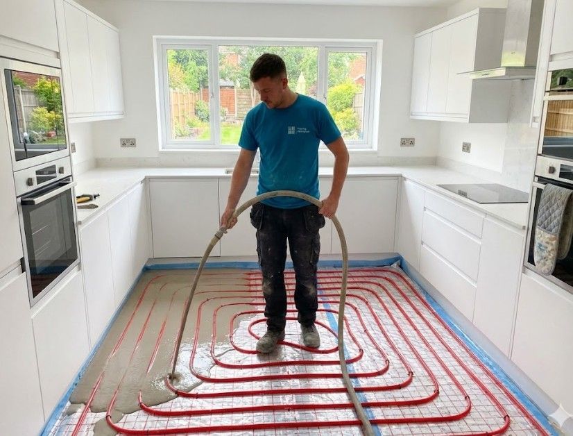 Flooring Nottingham applying liquid screed over underfloor heating pipes in a kitchen