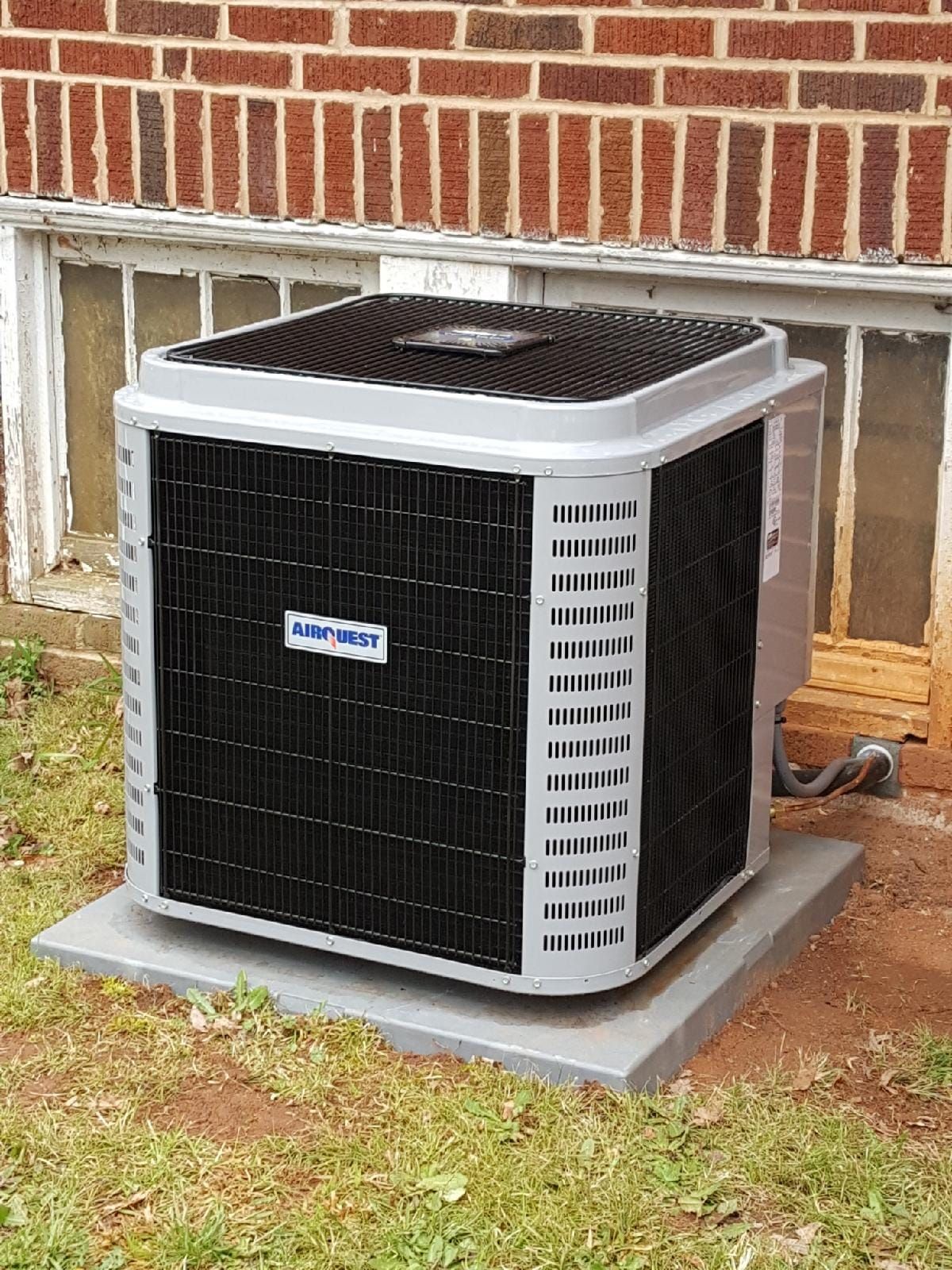 an air conditioner is sitting on a concrete base in front of a brick building .