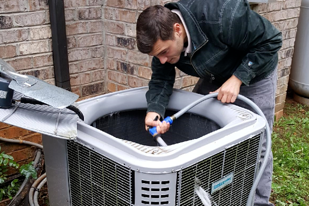 a man is cleaning an air conditioner with a hose .