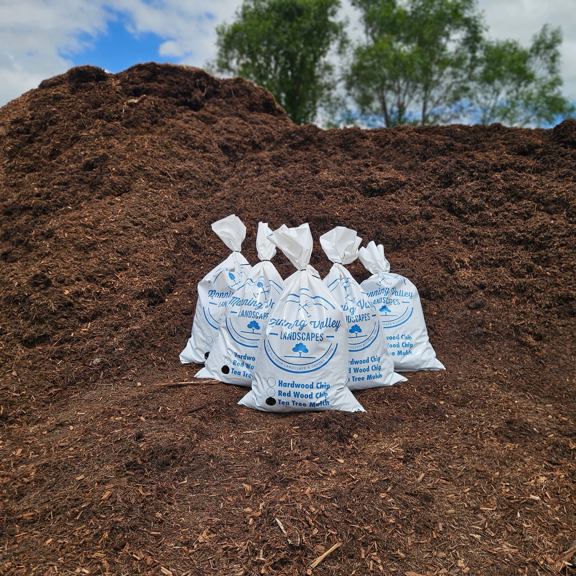 A Bunch of Bags of Mulch Are Sitting in Front of A Pile of Mulch — Manning Valley Landscapes in Wingham, NSW