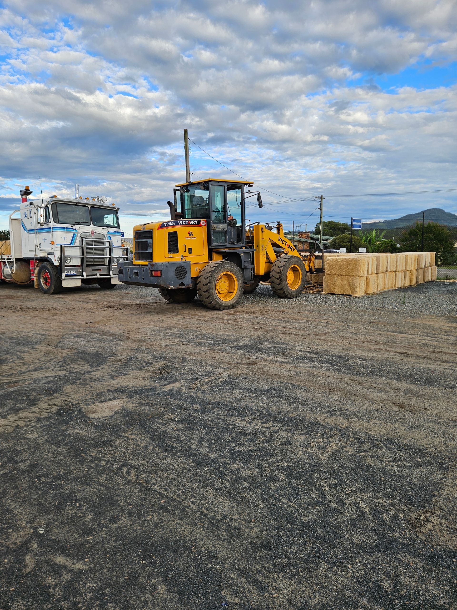Yellow Front-End Loader Loading A White Truck With Landscaping Materials — Manning Valley Landscapes in Wingham, NSW