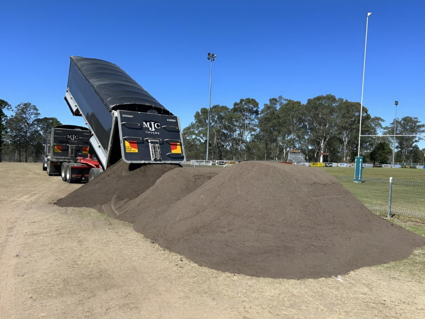 A Dump Truck is Dumping Dirt Into a Pile — Manning Valley Landscapes in Hallidays Point, NSW