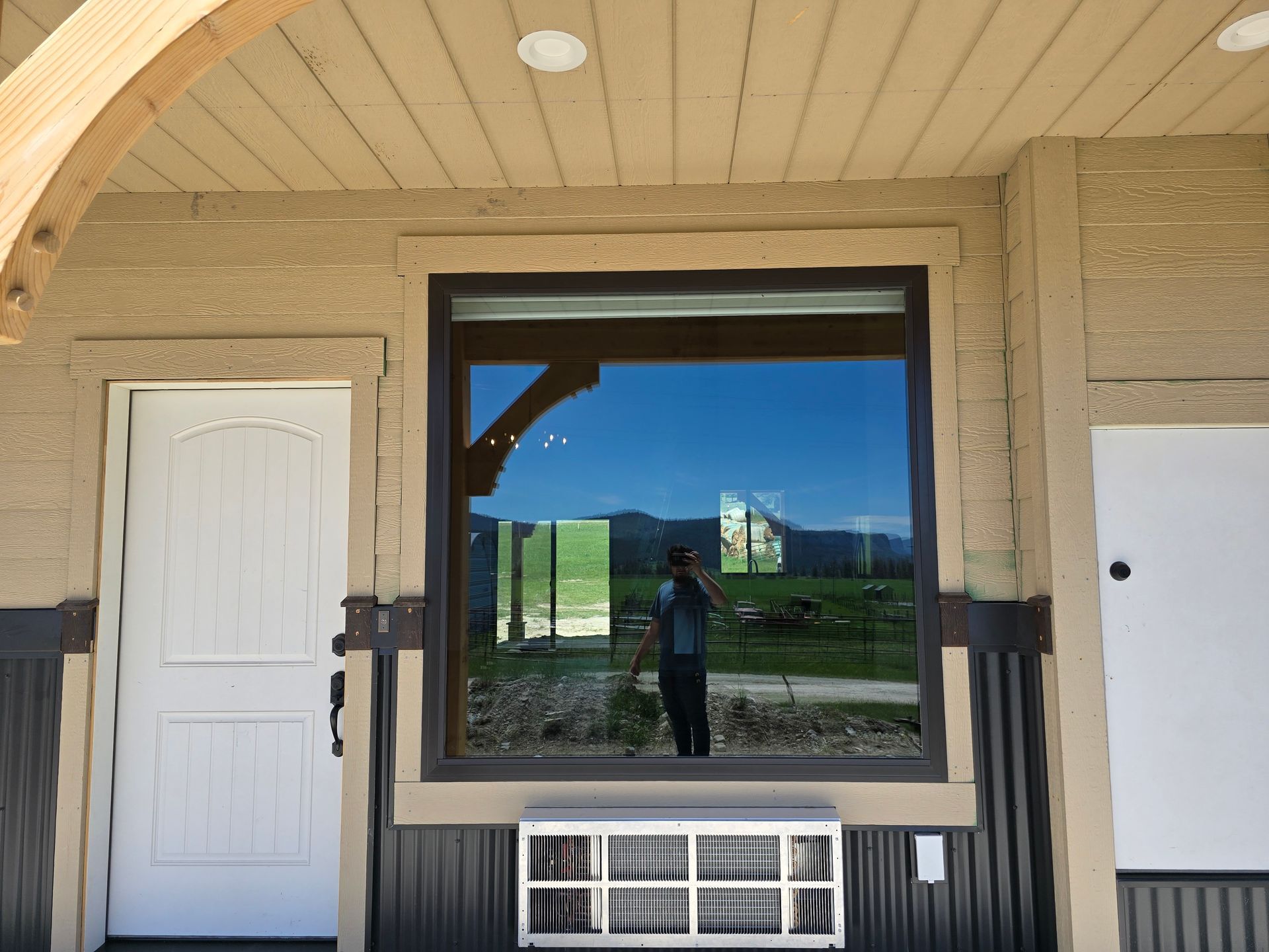 A window and white door on a beige exterior wall, with an air conditioning unit installed below the window.