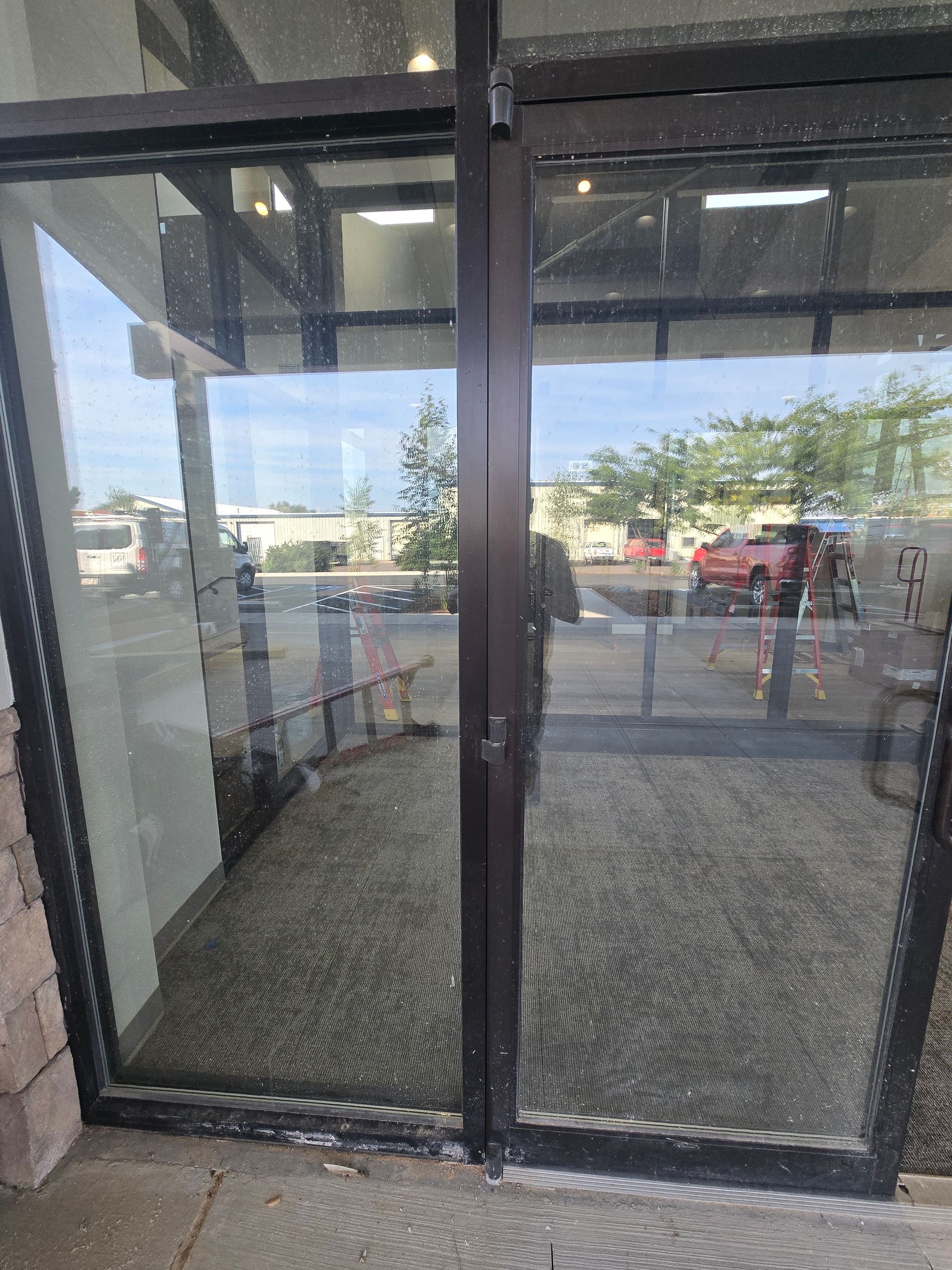 A set of glass double doors with black metal frames looking out onto a parking lot.