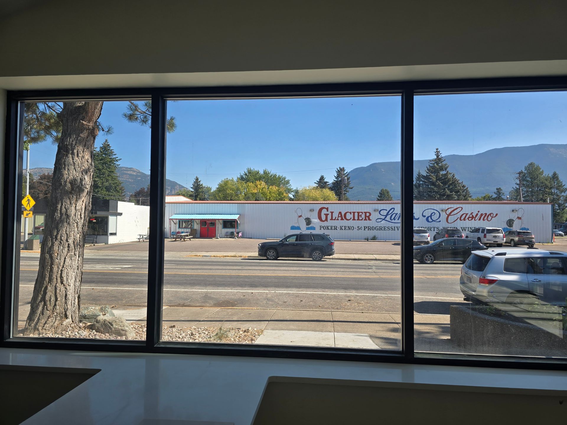 A view from a window showing a street with cars, a white building labeled 
