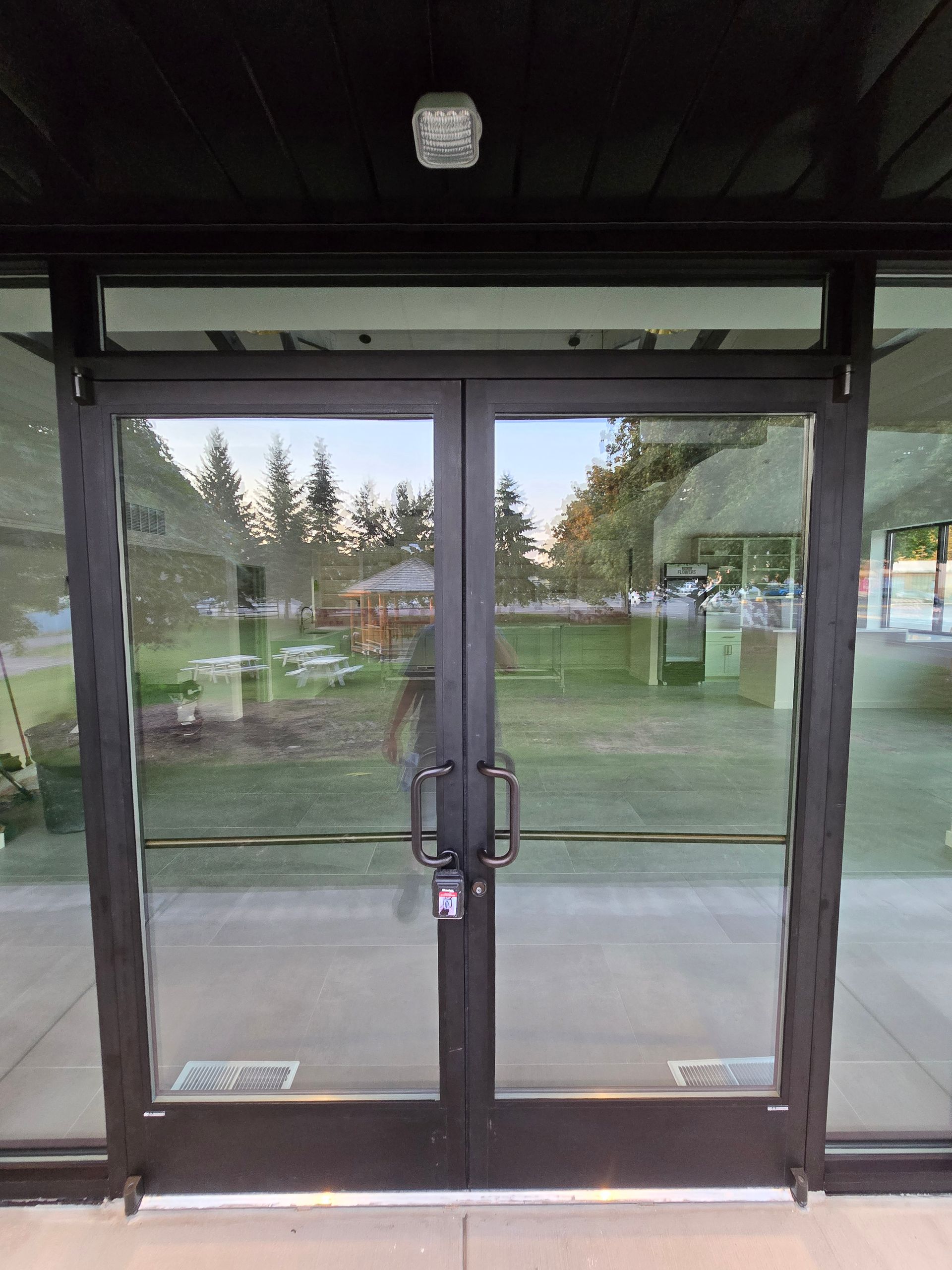 A set of double glass doors with a black frame and metal pull handles, viewed from the outside of a building.