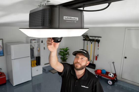 A man is installing a garage door opener on the ceiling.