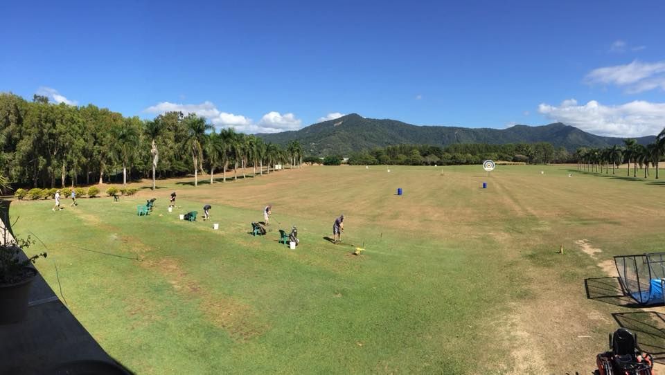 A panoramic view of a golf course with mountains in the background.
