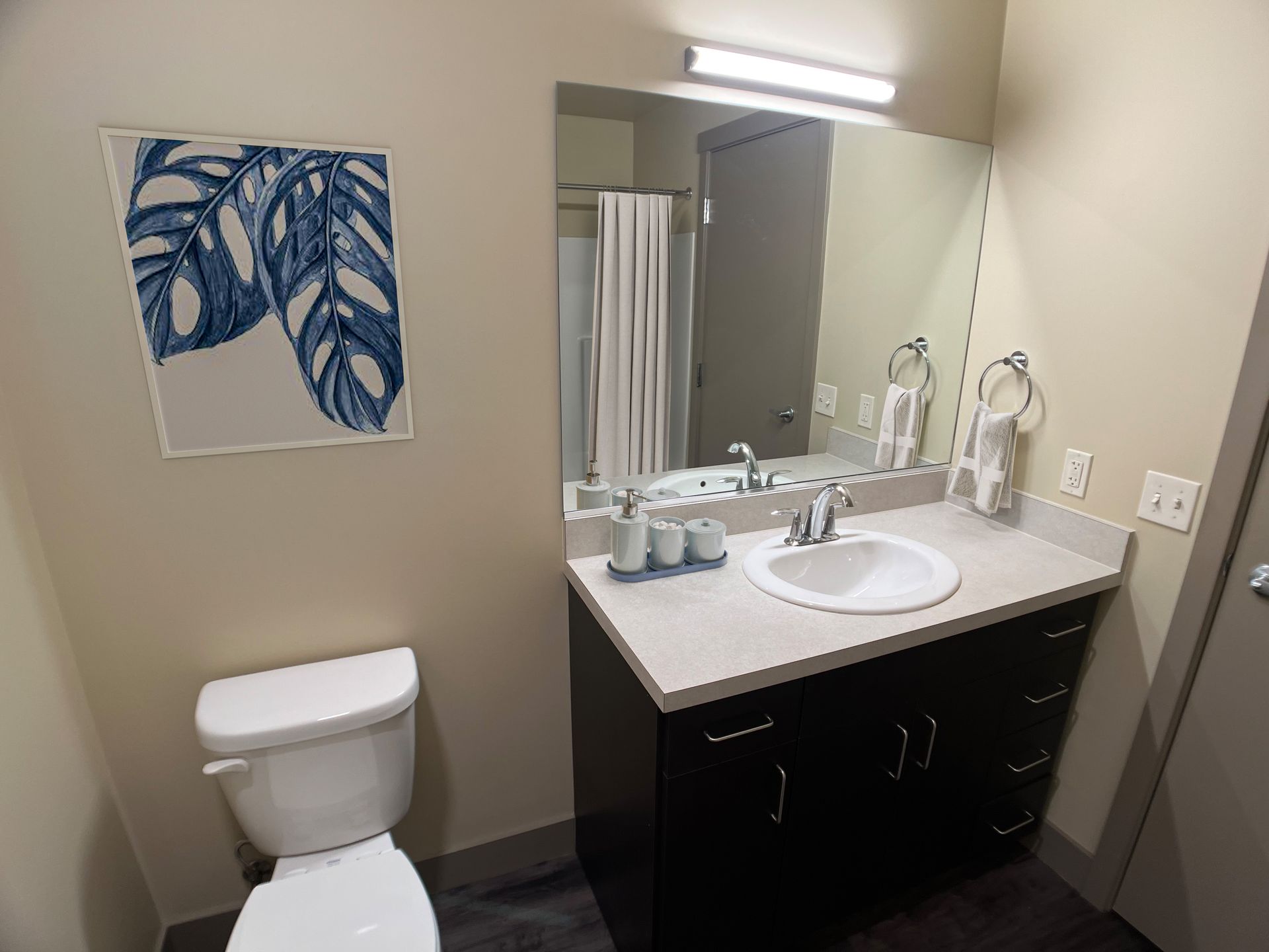 A bathroom with a toilet , sink and mirror.
