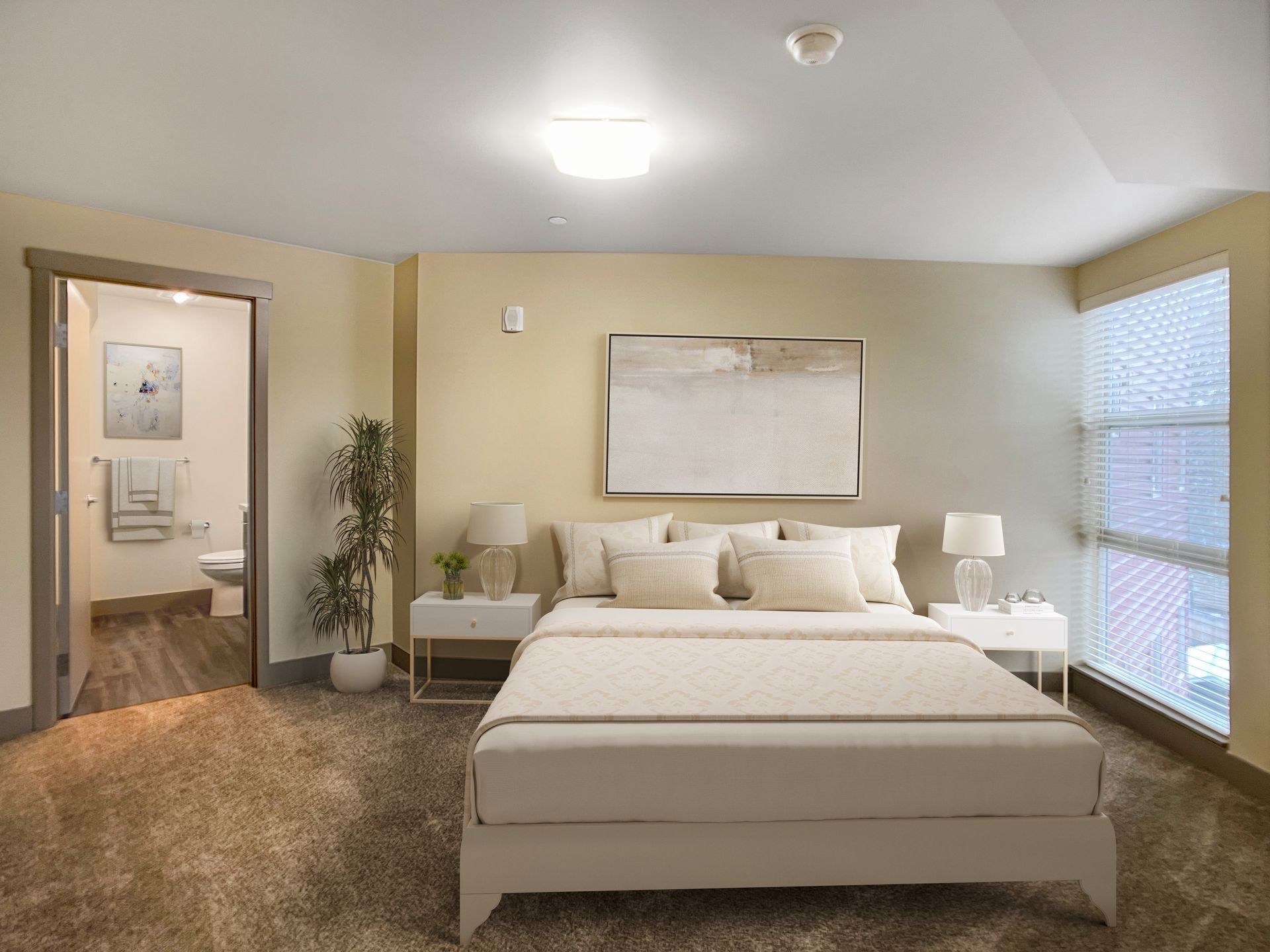 A bedroom with a large bed , nightstands , lamps and a bathroom.