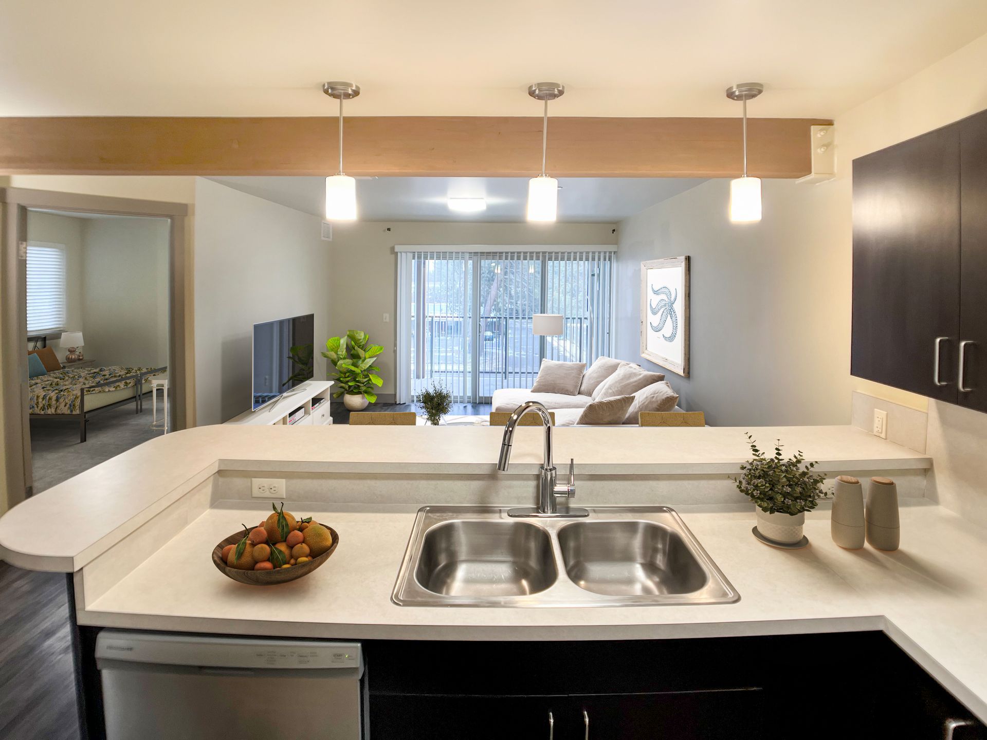 A kitchen with a sink and a bowl of fruit on the counter.