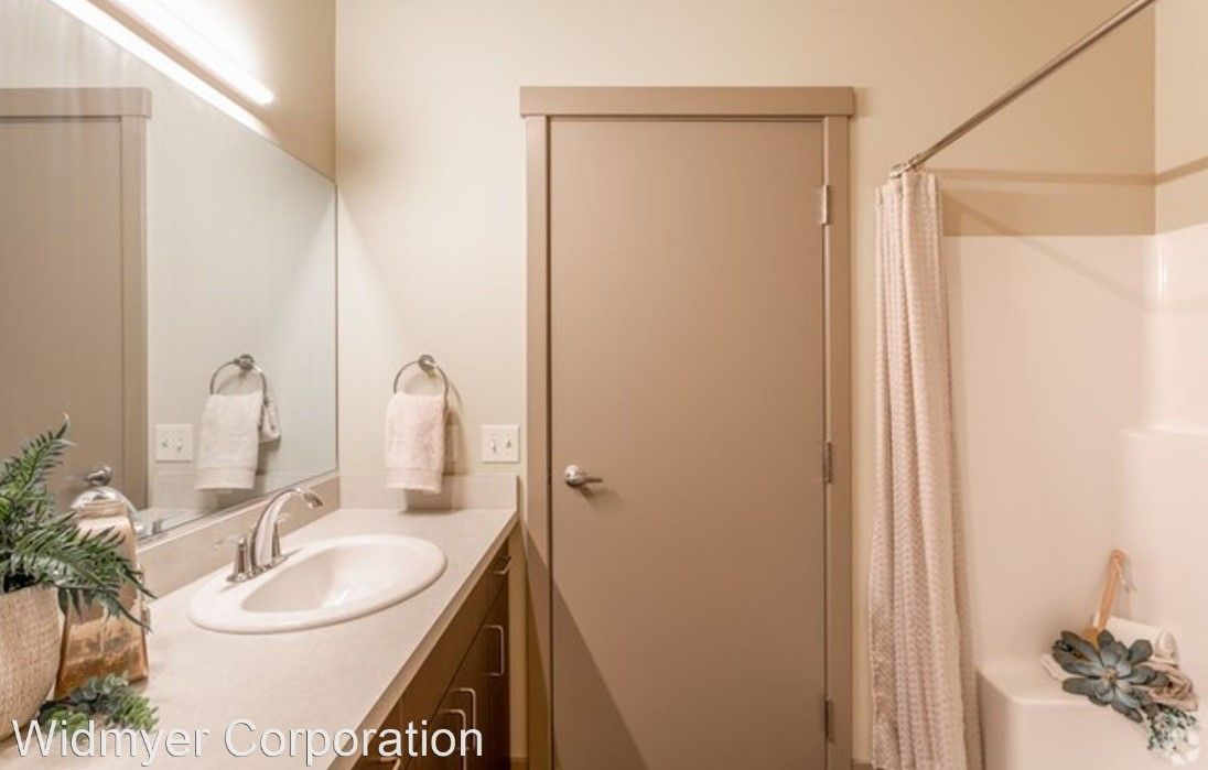 A bathroom with a sink , mirror and shower.