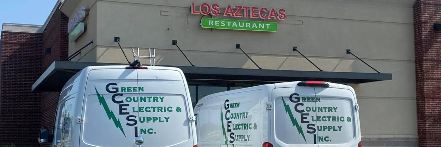 Two white Green Country Electric & Supply Inc. vans parked in front of Los Alteras Restaurant.