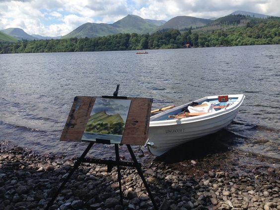 A painting on an easel next to a boat on a lake