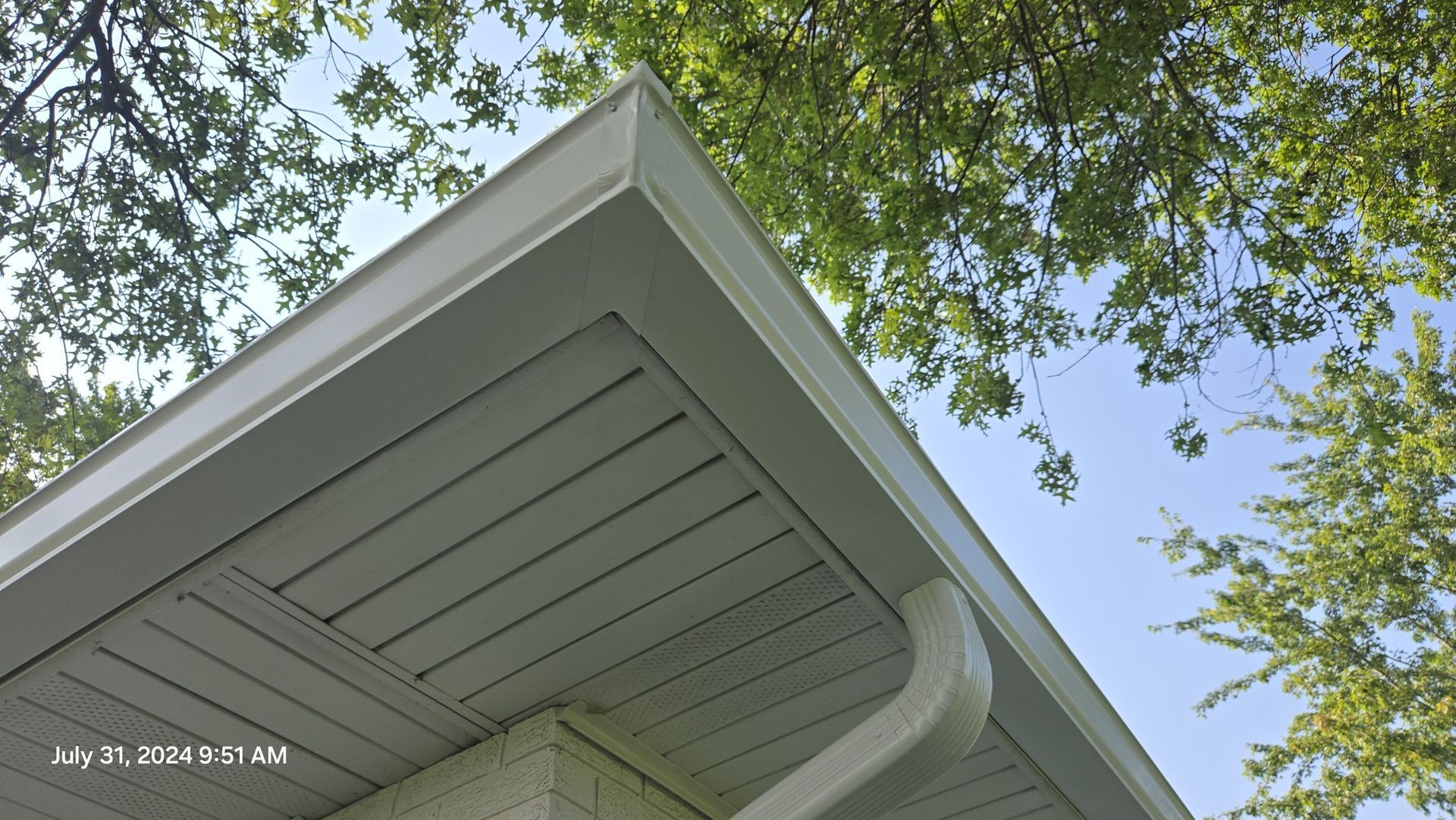 Looking up at the roof of a house with trees in the background