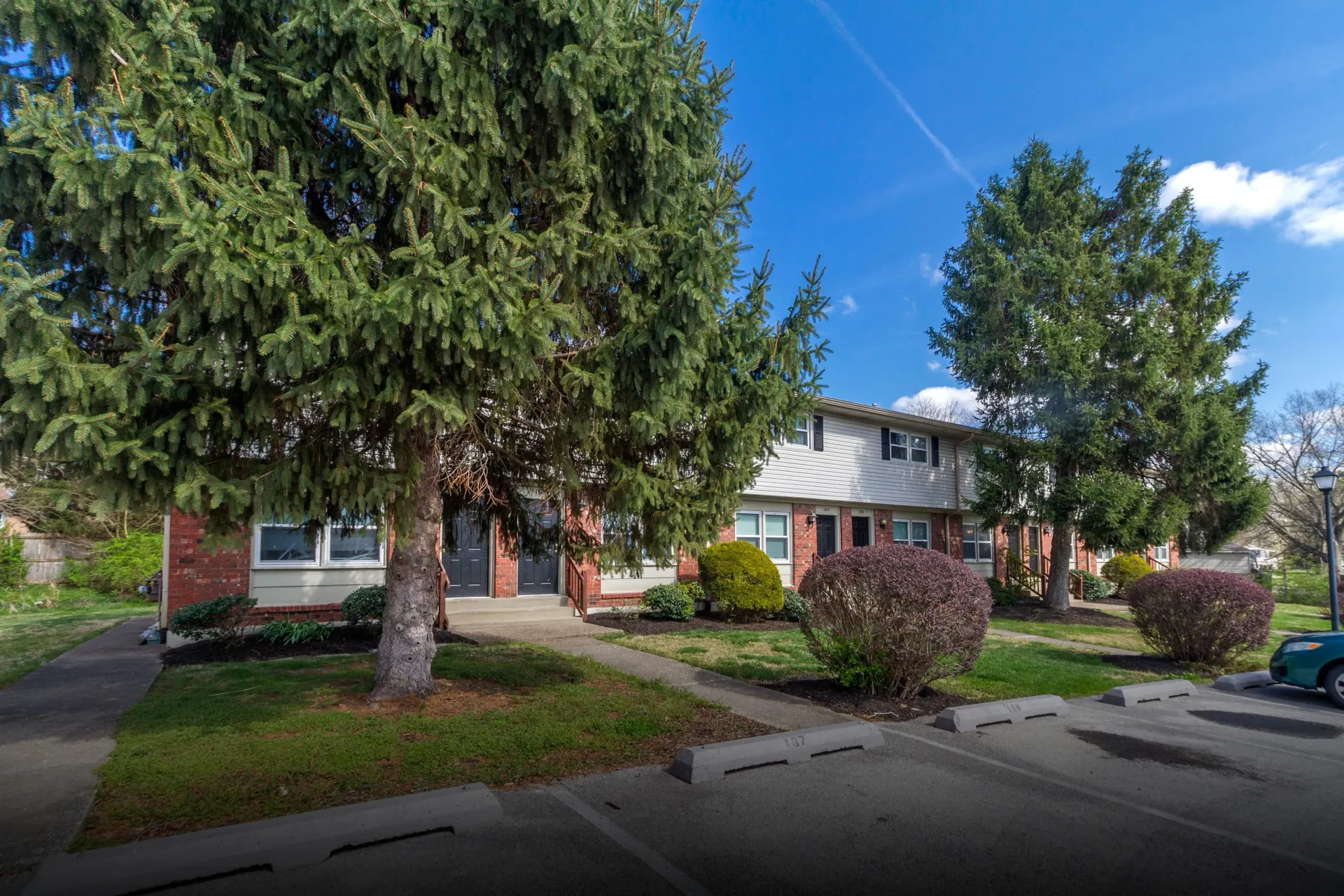 Apartment building with trees and shrubs on a sunny day.