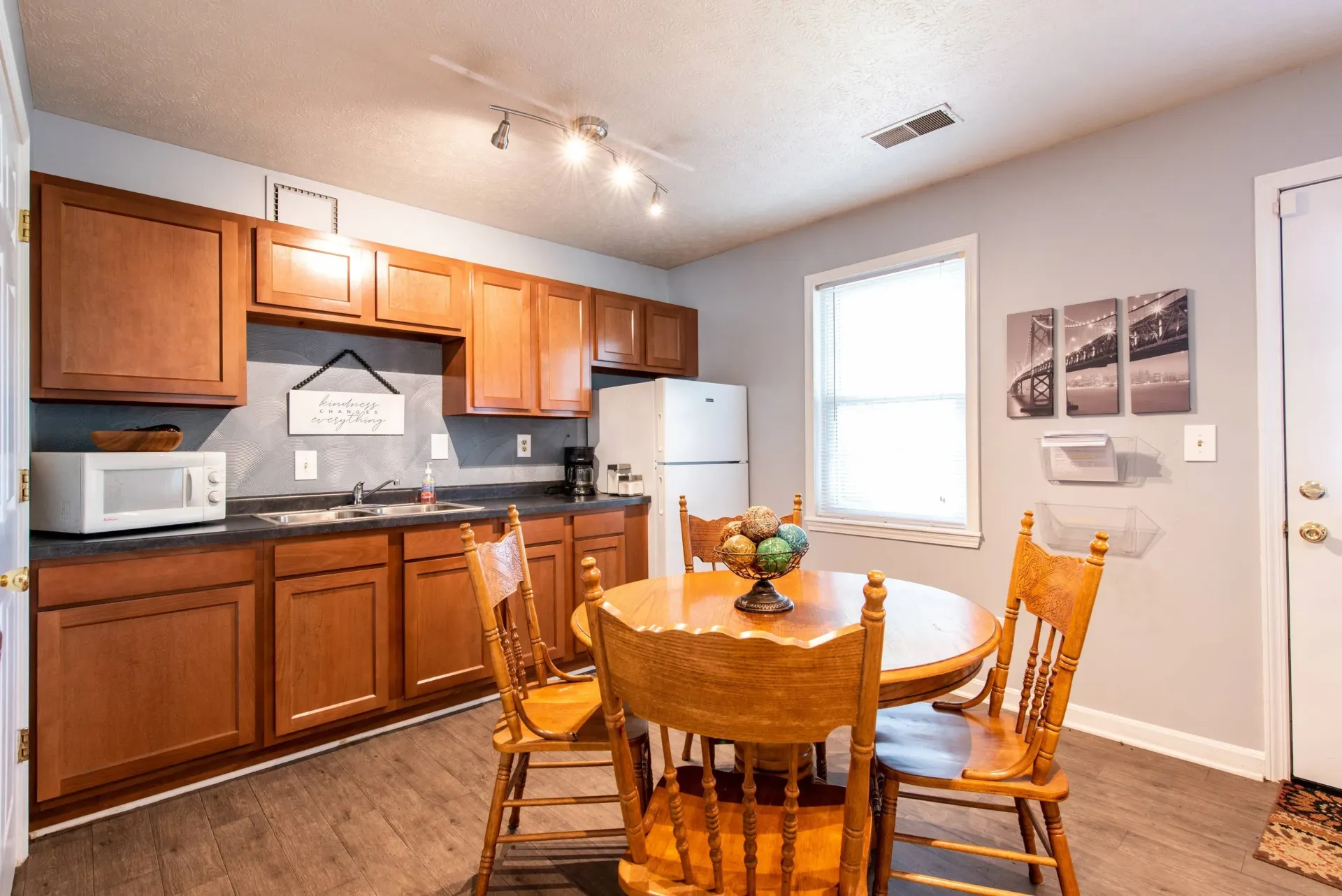 A kitchen with wooden cabinets, a table, chairs, and a refrigerator.