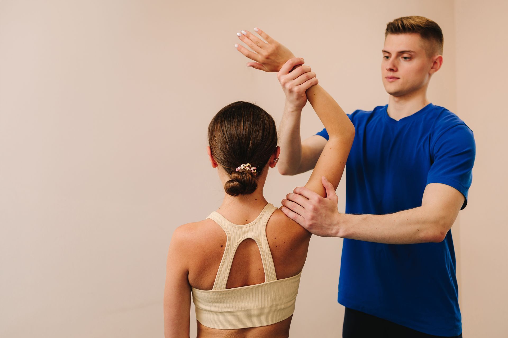 Physical therapist assisting a woman with arm exercises.