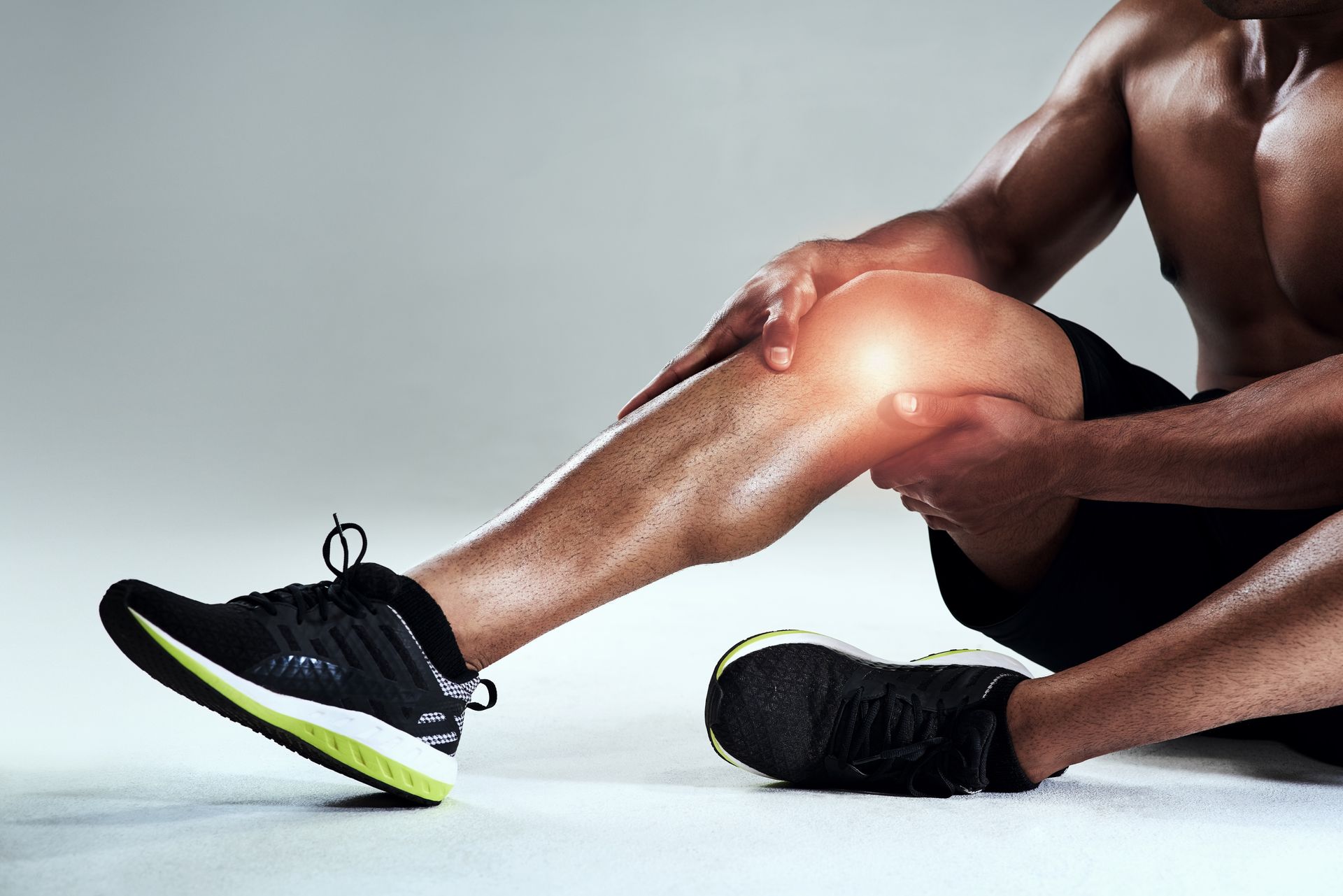 Athlete sitting and holding his knee with a highlighted pain spot.