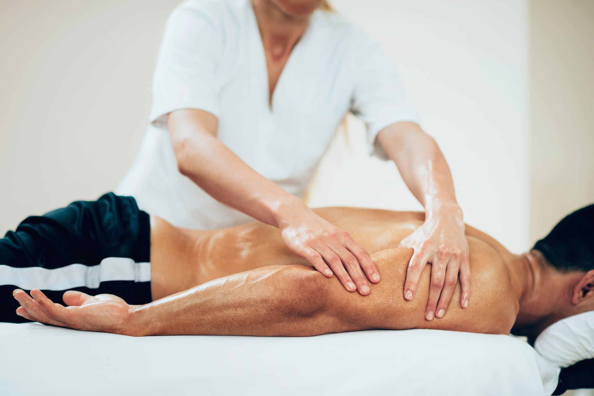 Therapist giving a back massage to a man lying on a table.