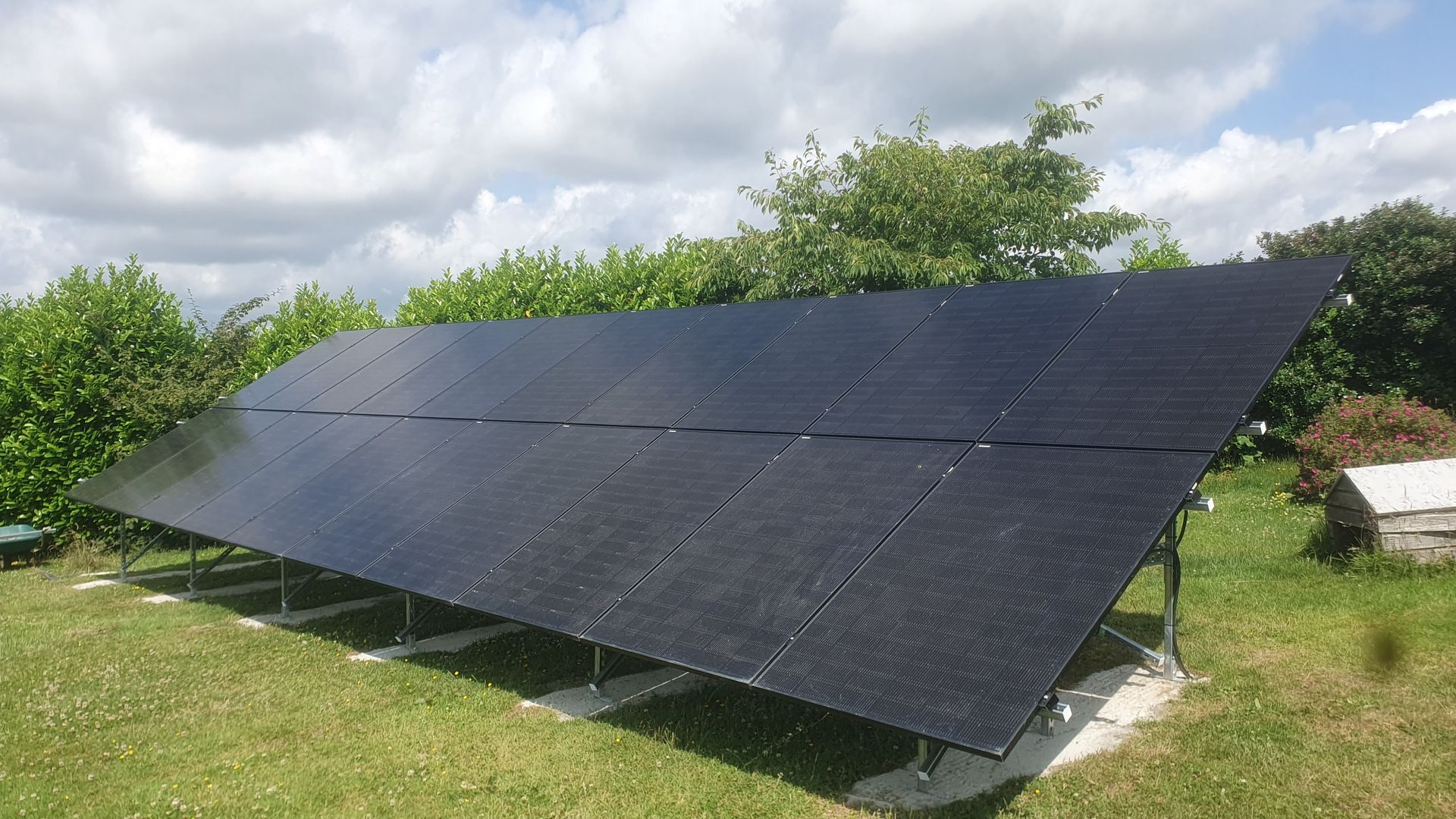 A row of solar panels sitting on top of a lush green field.