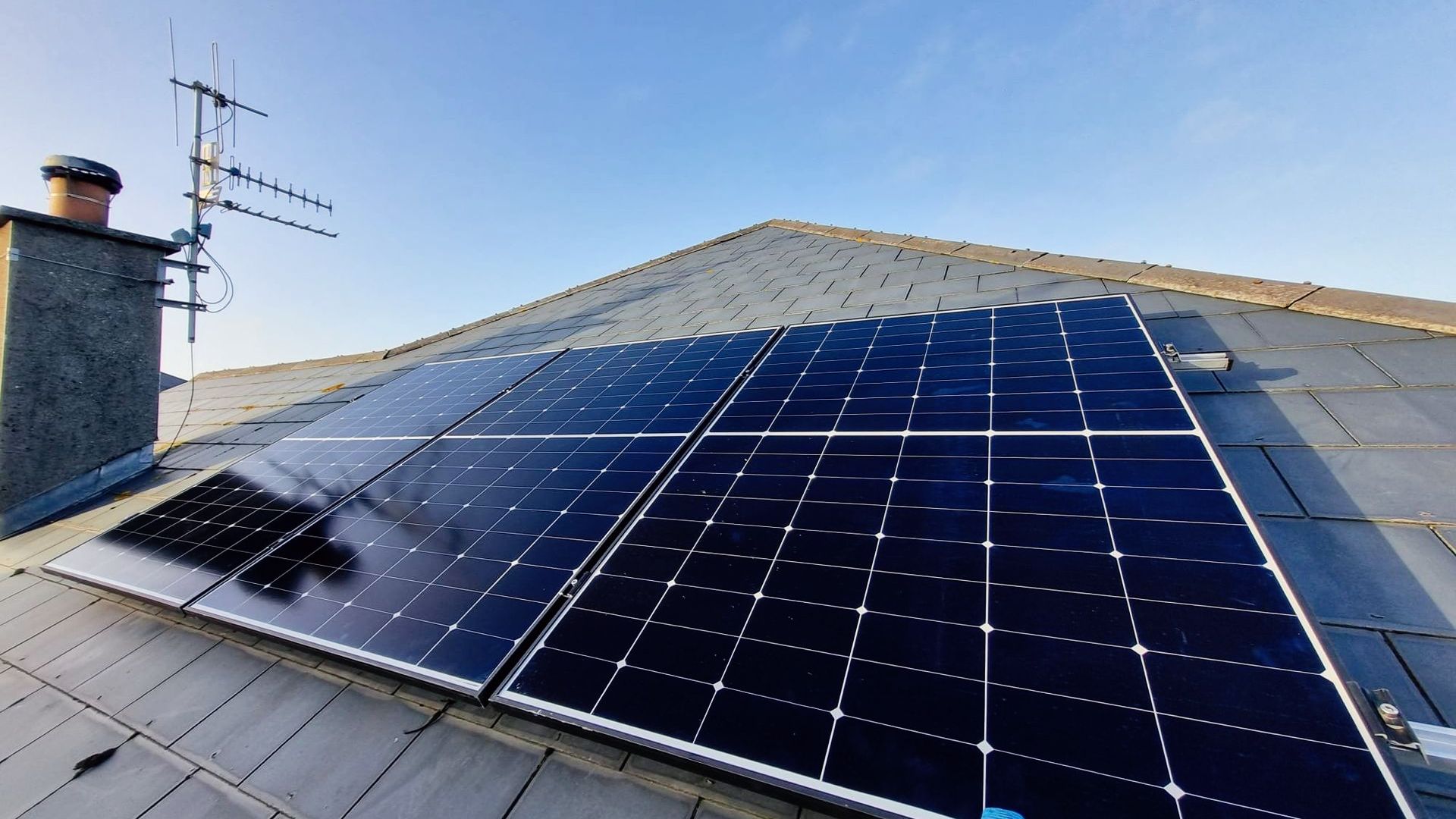 A row of solar panels are sitting on top of a roof.