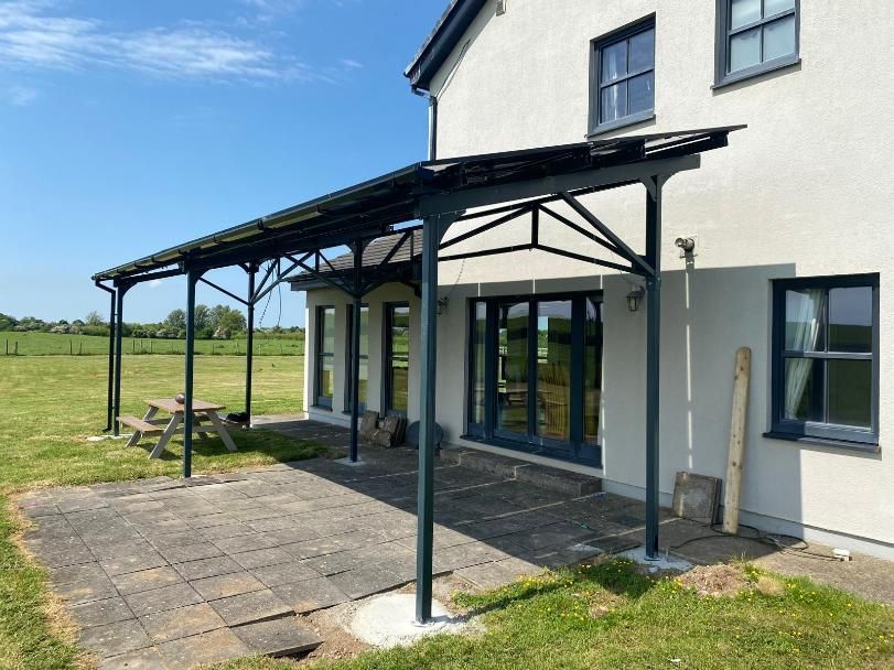 A white house with a covered patio and a picnic table in front of it.
