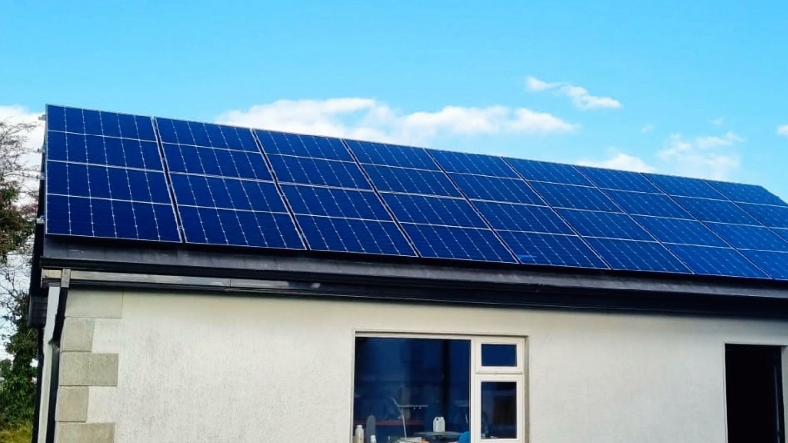 A white house with blue solar panels on the roof