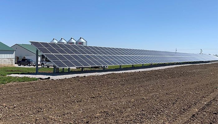 A row of solar panels are sitting on top of a dirt field.