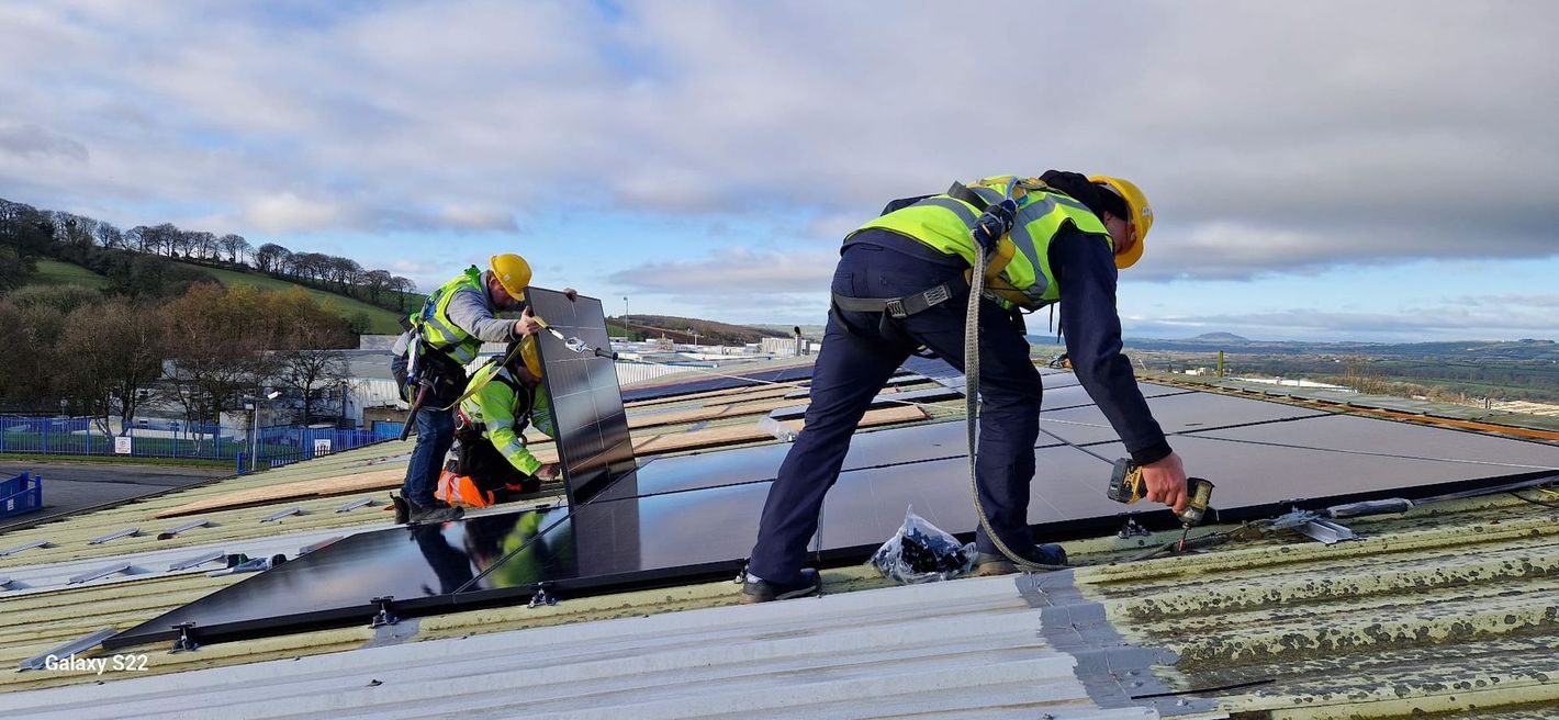 A group of construction workers are installing solar panels on a roof.