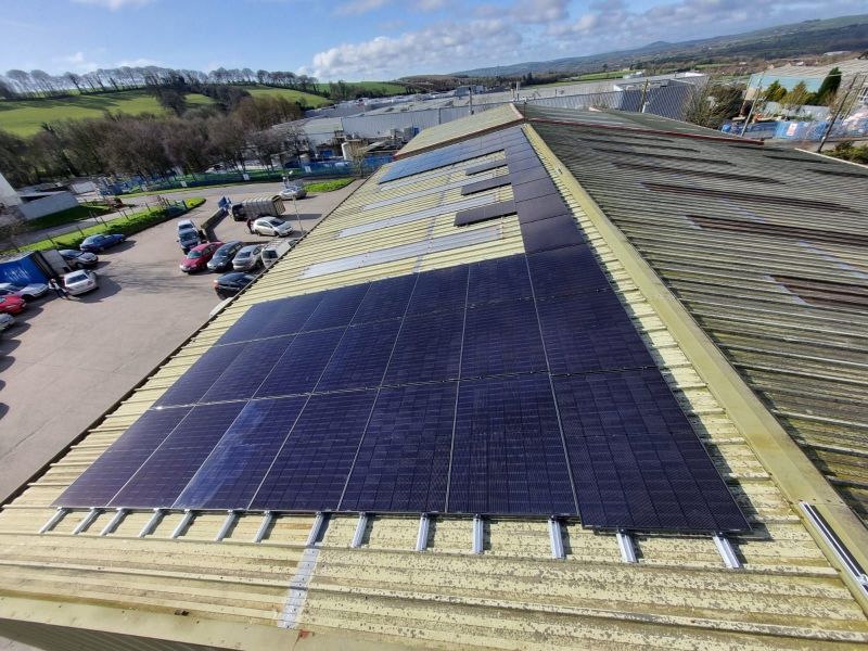 There are many solar panels on the roof of a building.