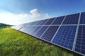A row of solar panels sitting on top of a lush green field.