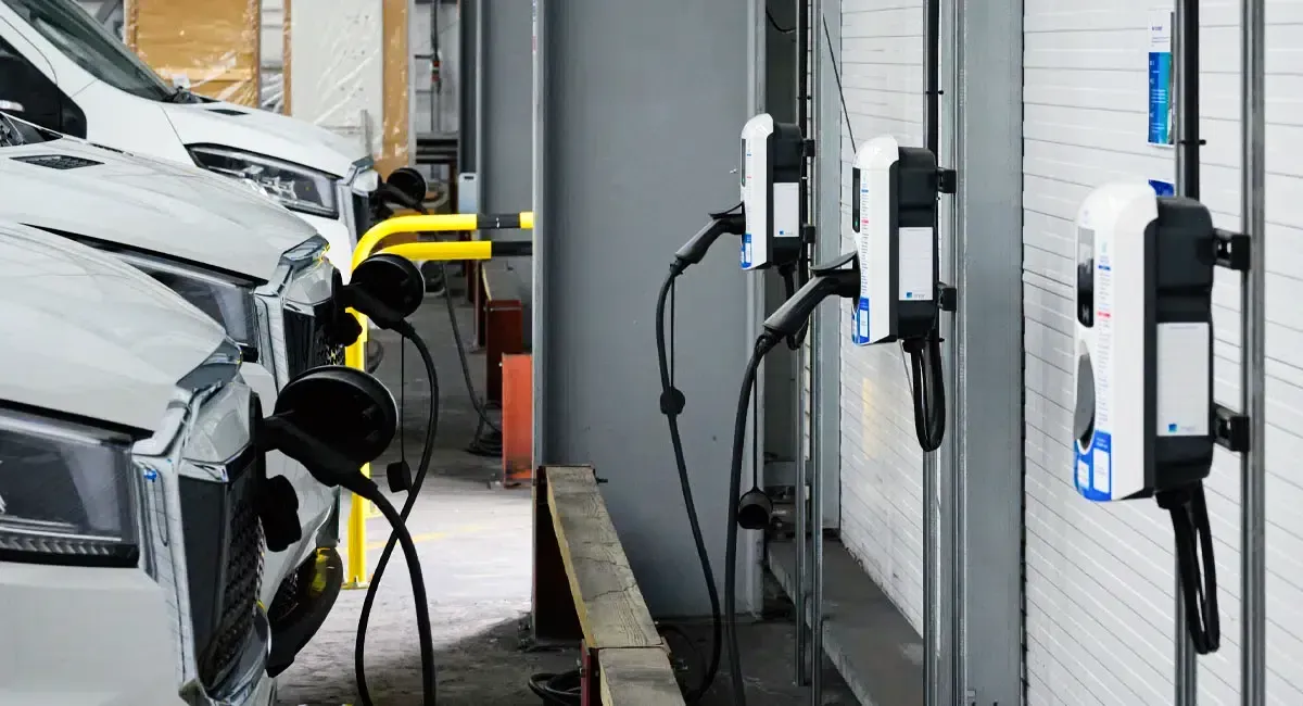 A white van is being charged at a charging station.