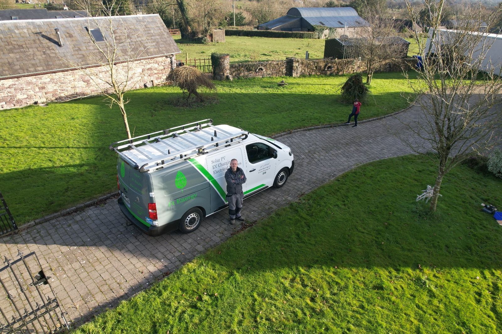 A man is standing next to a van in a driveway.