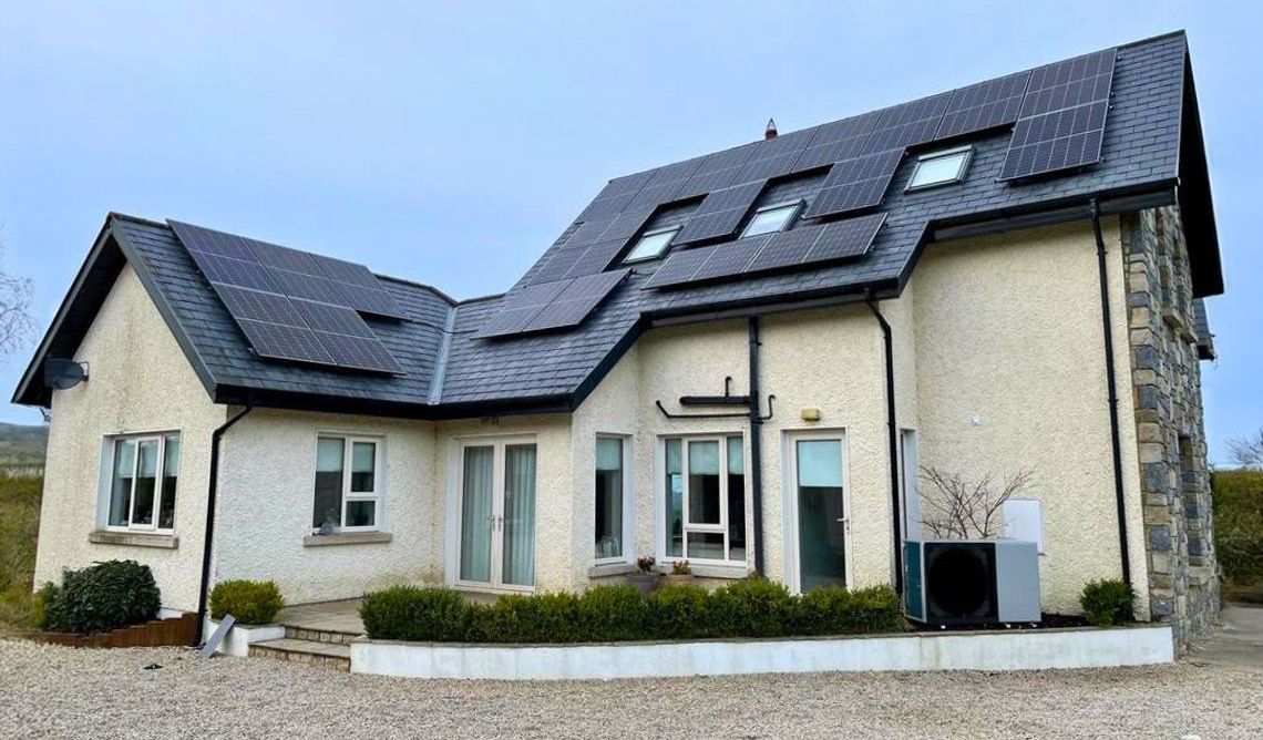 A white house with a black roof and solar panels on it