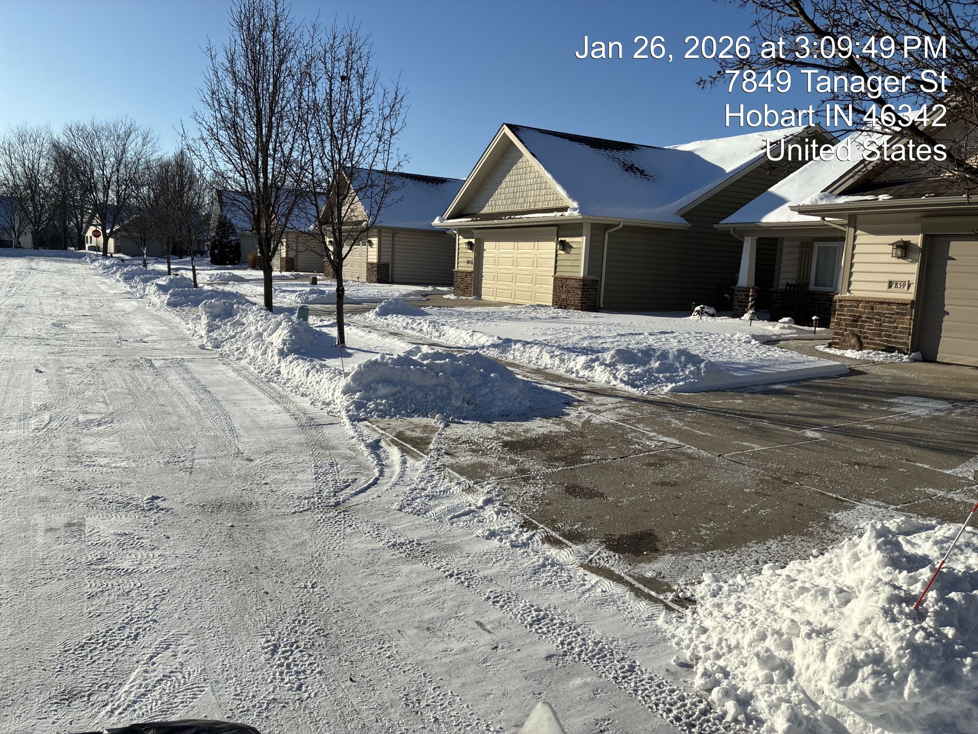 Snowy residential street with houses and a driveway on a clear winter day