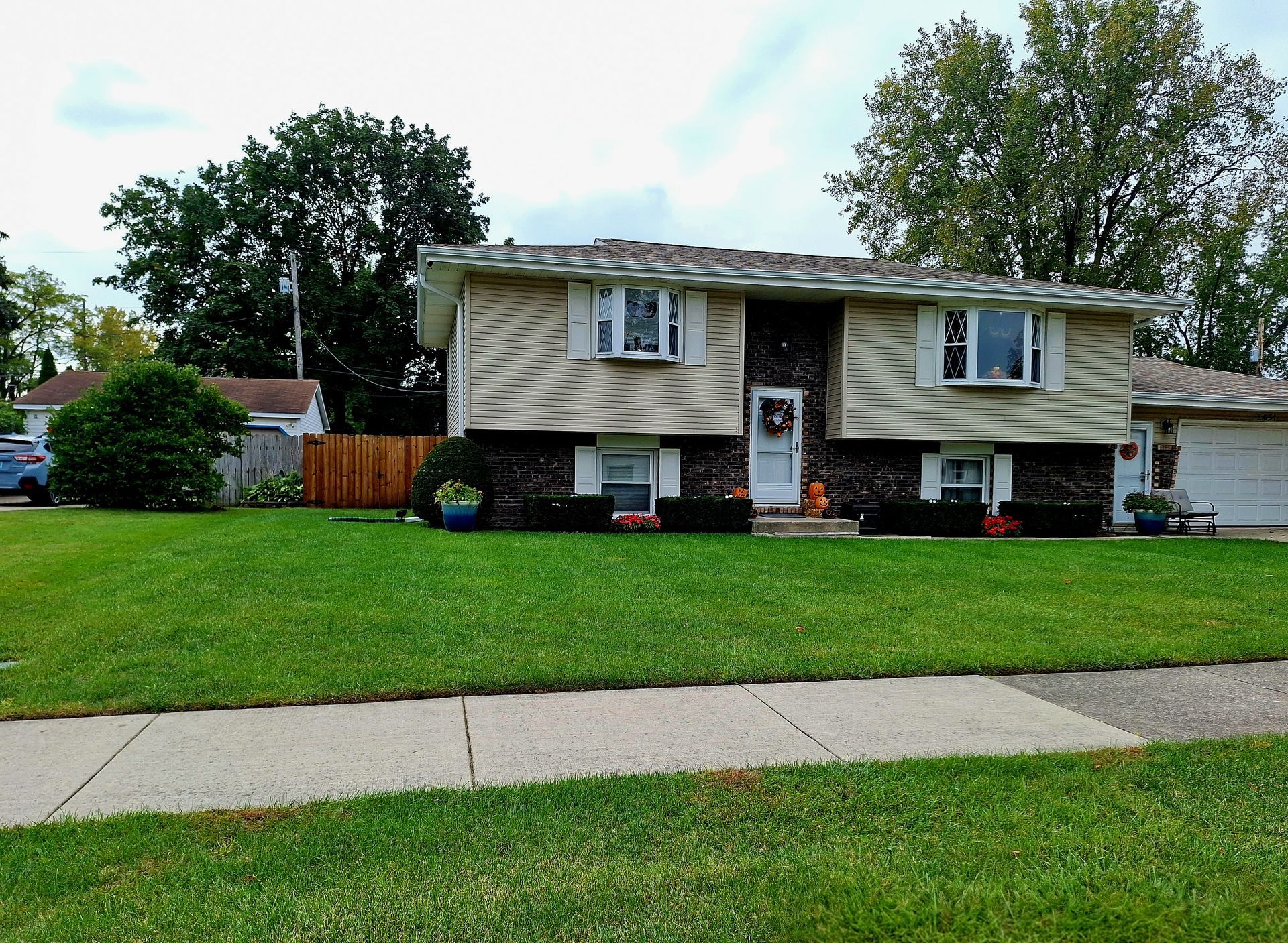 Suburban house with tan siding, green lawn, and a sidewalk in front