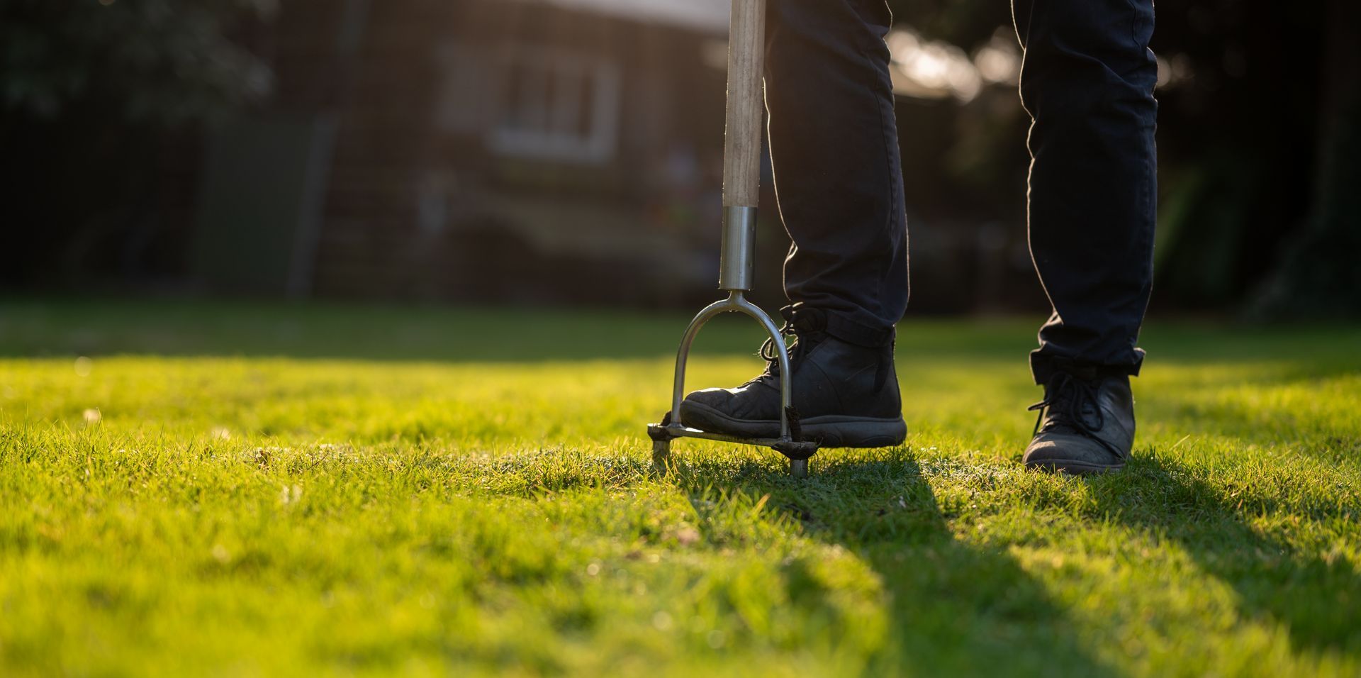 Person standing on a lawn with a golf club, ready to putt in the sunlight