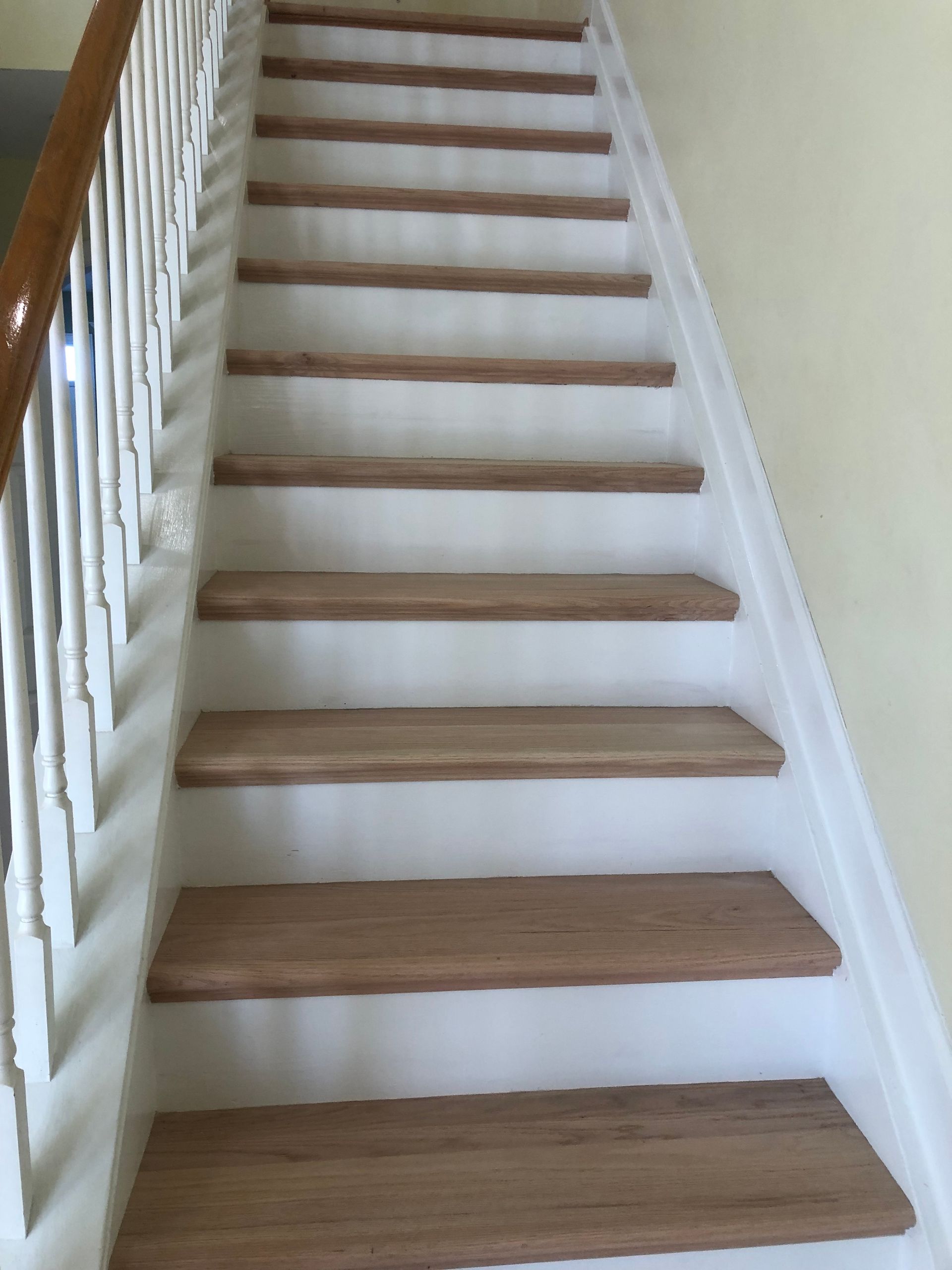 A staircase with new wooden steps and a white railing