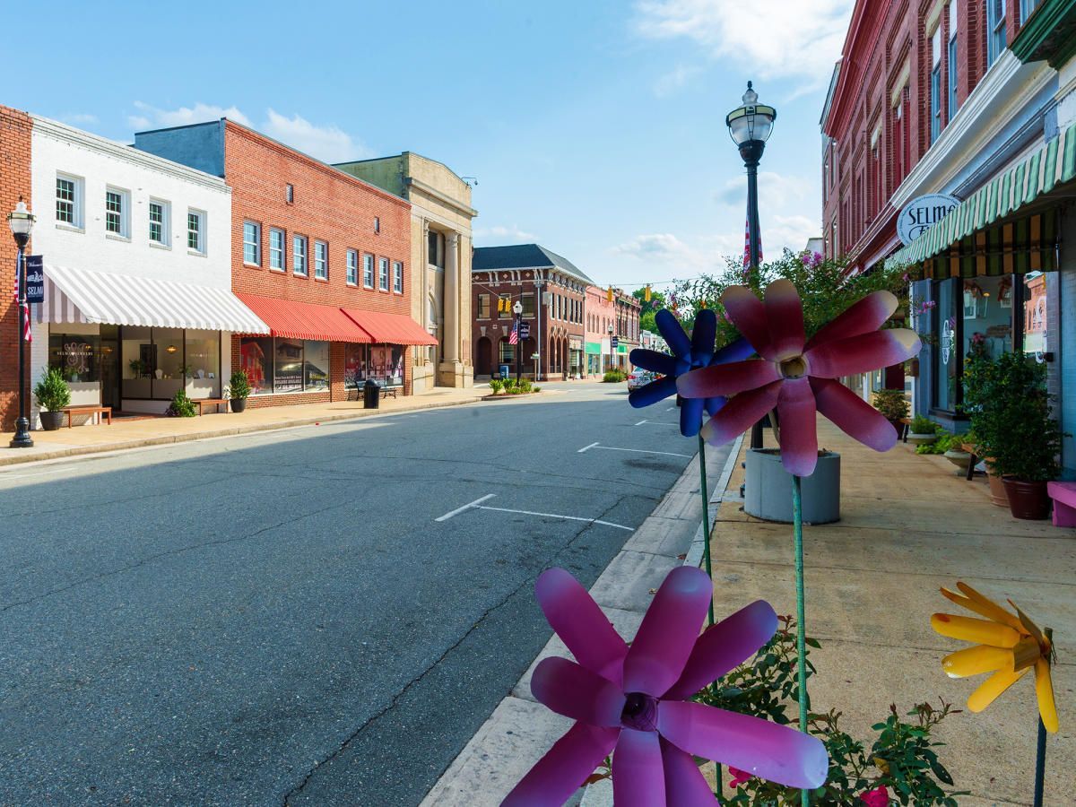 Street view of downtown Smithfield area with brick buildings, flowers in foreground, and blue sky.