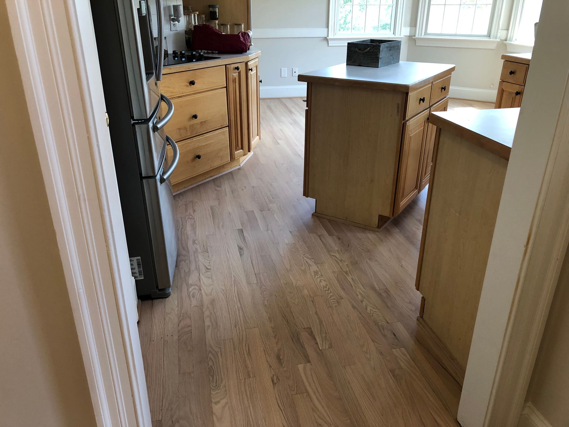 Wooden kitchen floor with light wooden cabinets and an island.