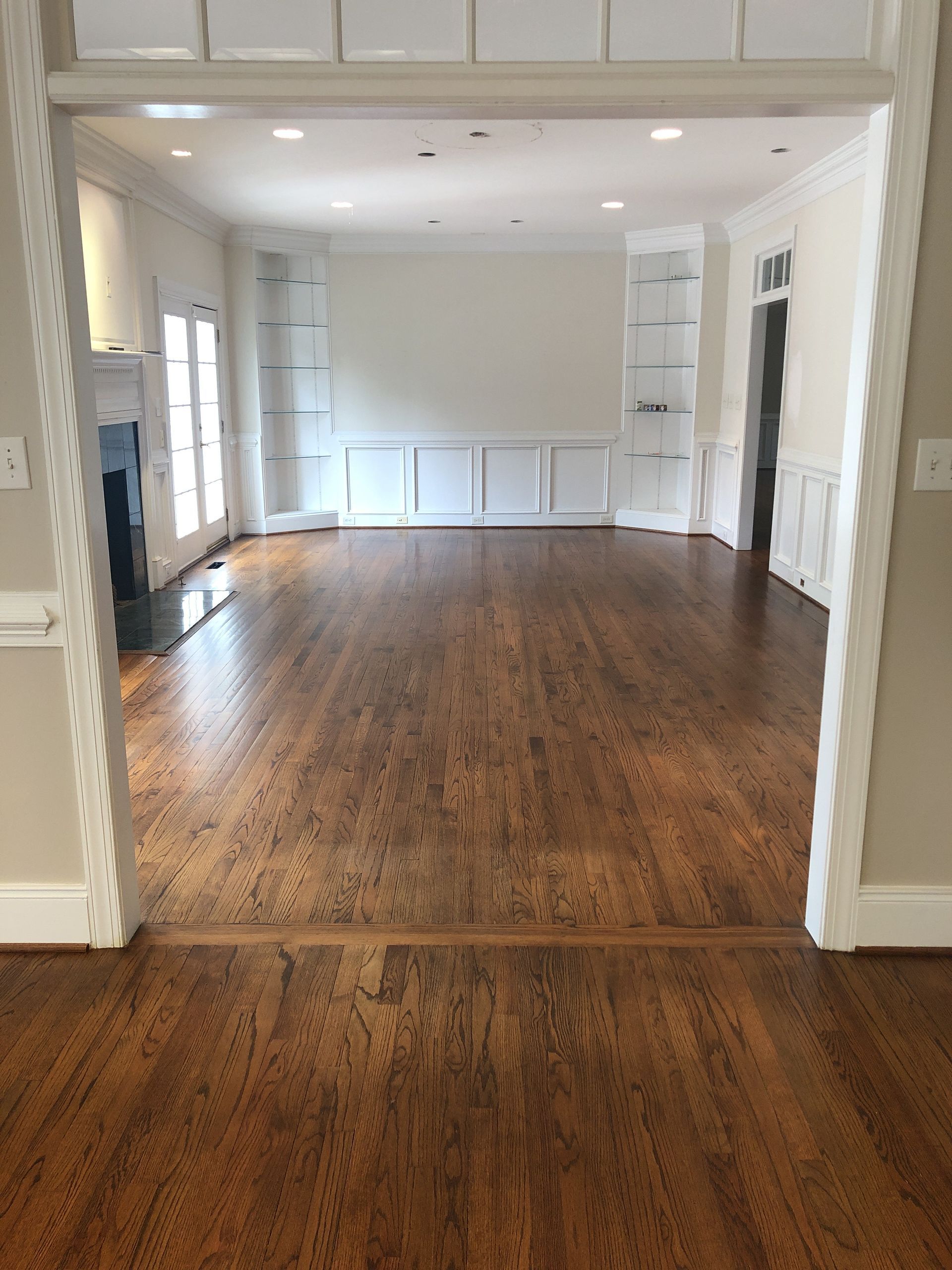 A large empty room with hardwood floors and white walls.