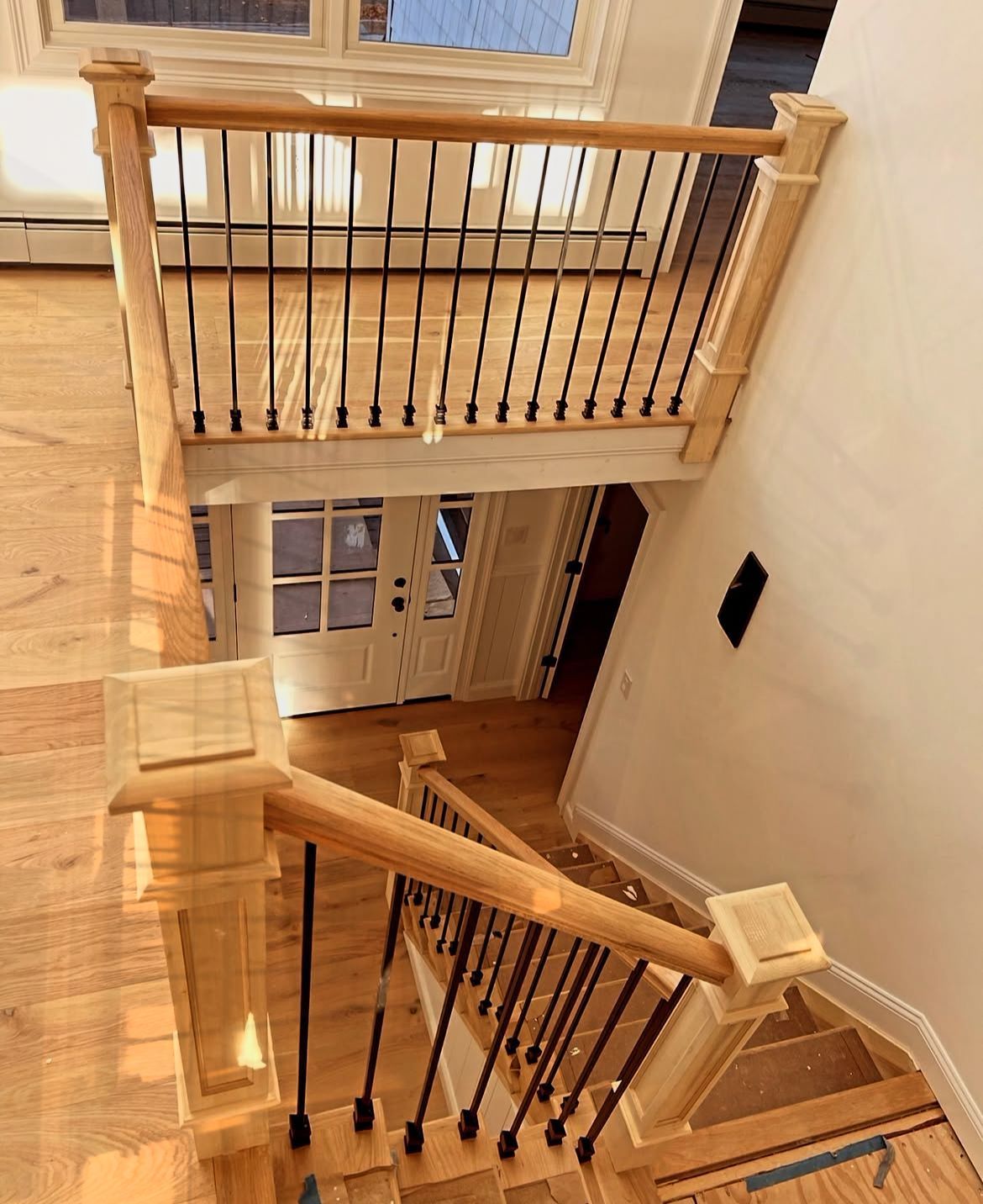 Wooden staircase with black railings, leading to a front door with white trim. Stair installation company Chapel Hill.